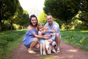 Glückliche Familie kniened vor Baumallee fotografiert