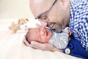 Vater lacht sein neugeborenes Baby an