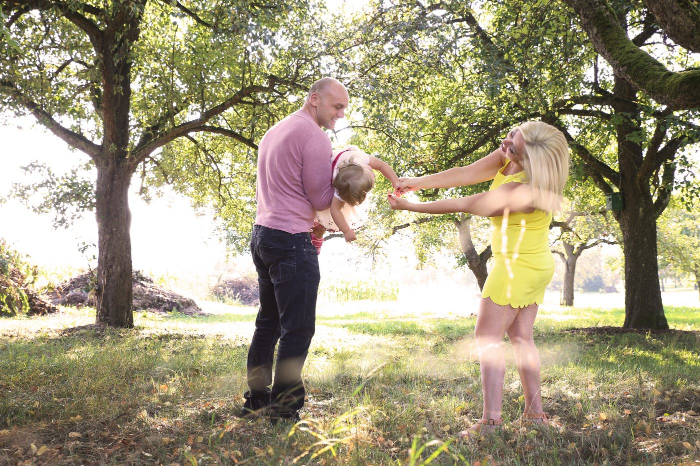 Kind möchte zur Mutter während es beim Vater auf dem Arm liegt fotografiert unter Obstbäumen