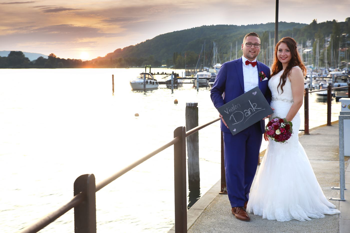 Bräutigam mit blauem Anzug hält eine Schild mit dem Schtiftzug vielen Dank in der Hand