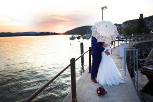 Brautpaar am Bodensee fotografiert verteckt sich unter einem Schirm im Vintagelook