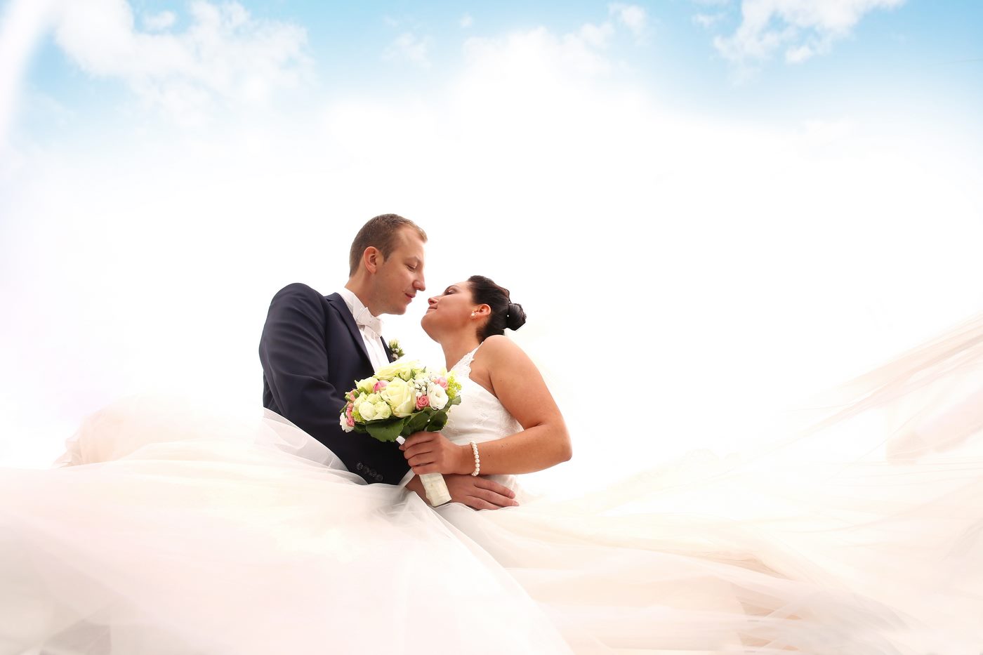 Brautpaar schaut sich unter blauem Himmel in die Augen