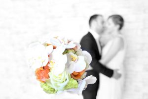 Blumen fotografiert mit Brautpaar verschwommen im Hintergrund