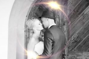 Brautpaar küsst sich an einem Holztor schwarz-weiß