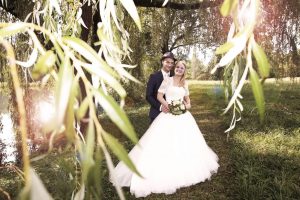 Brautpaar während Hochzeitsfotografie unter einem Baum