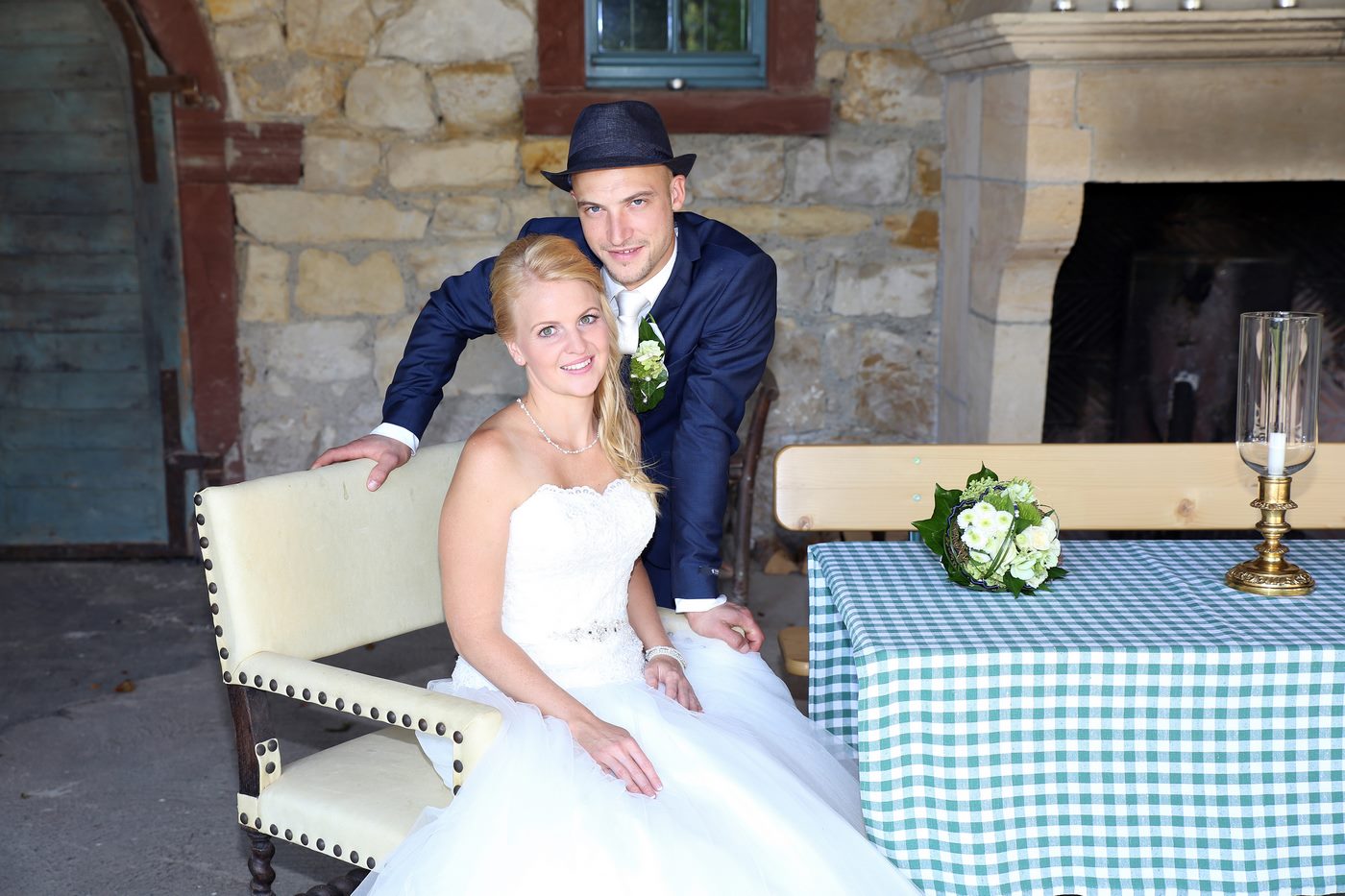 Ehemann mit Hut stehend hinter seiner Frau während eines Hochzeitsshootings