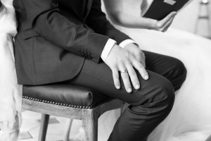 Ehemann hält während Traun seine Hand auf dem Schoß in schwarzweiß fotografiert