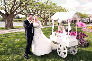 Brautpaar beißt in Lutsche neben einem Candycart