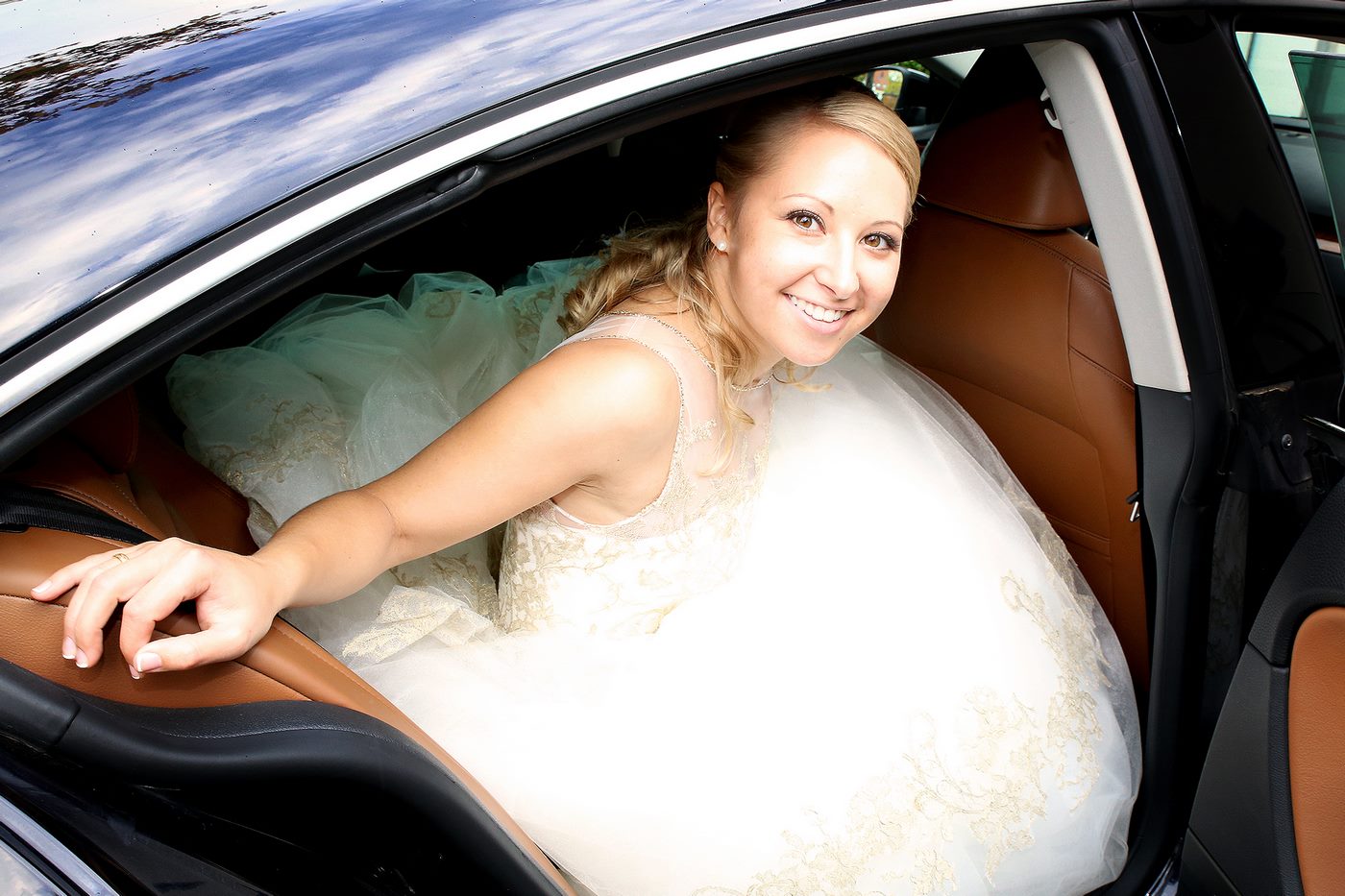 Braut mit weißem Brautkleid im Auto fotografiert