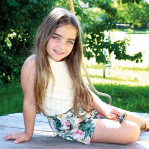 Mädchen sitzend auf Holzpodest