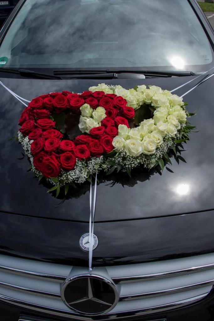 Autoblumenschmuck in Form von zwei Herzen in weiß-rot auf einem schwarzem Mercedes