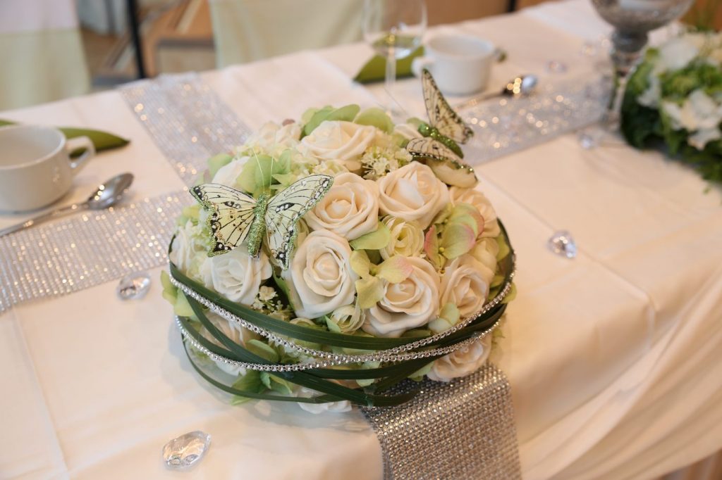 Tischgesteck aus weißen Rosen auf Glitzerbordüren