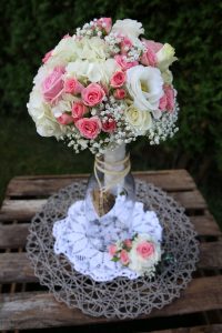 Blumenstrauss mit Rosa Rosen in Vase auf Holztisch mit vintage Tischdecke