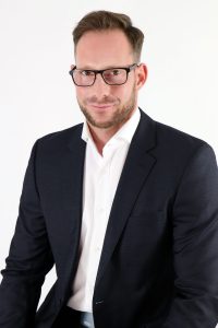 Bewerbungsfoto mit schwarzem Anzug vor einem weißem Hintergrund